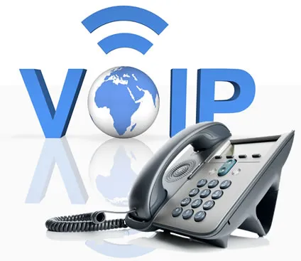 Desk phone sits before large blue “VOIP” letters, a globe, and wireless signal symbol on a reflective white surface.