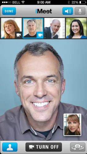 Smartphone screen displays a smiling gray-haired man on a video call, with four participant thumbnails and call controls.
