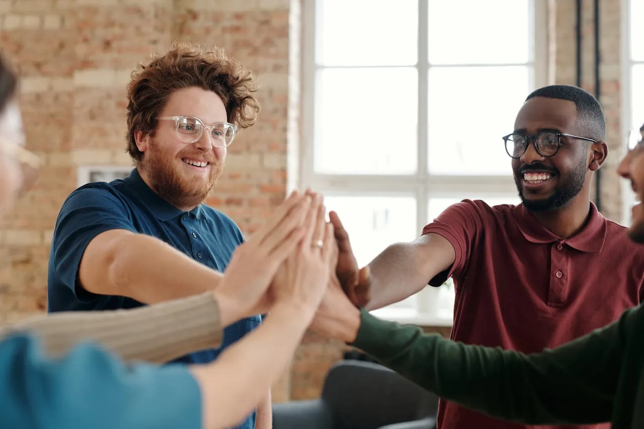 Team celebrating success with high fives in bright indoor space.