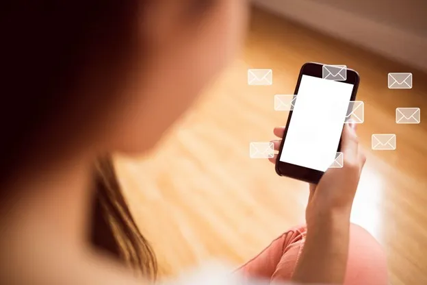 Woman using smartphone with email notification on warm background.