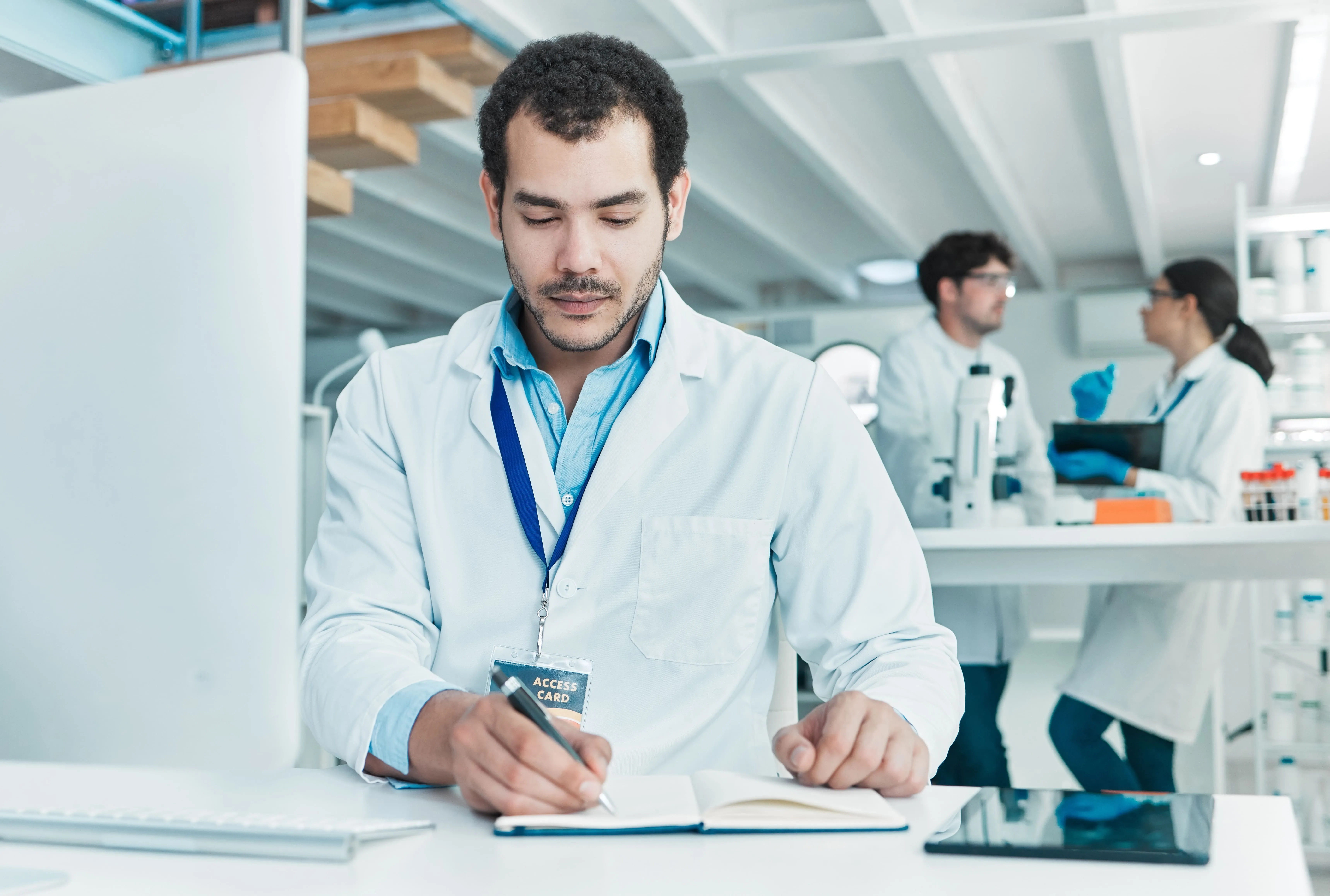 Scientist writing notes in lab with access card