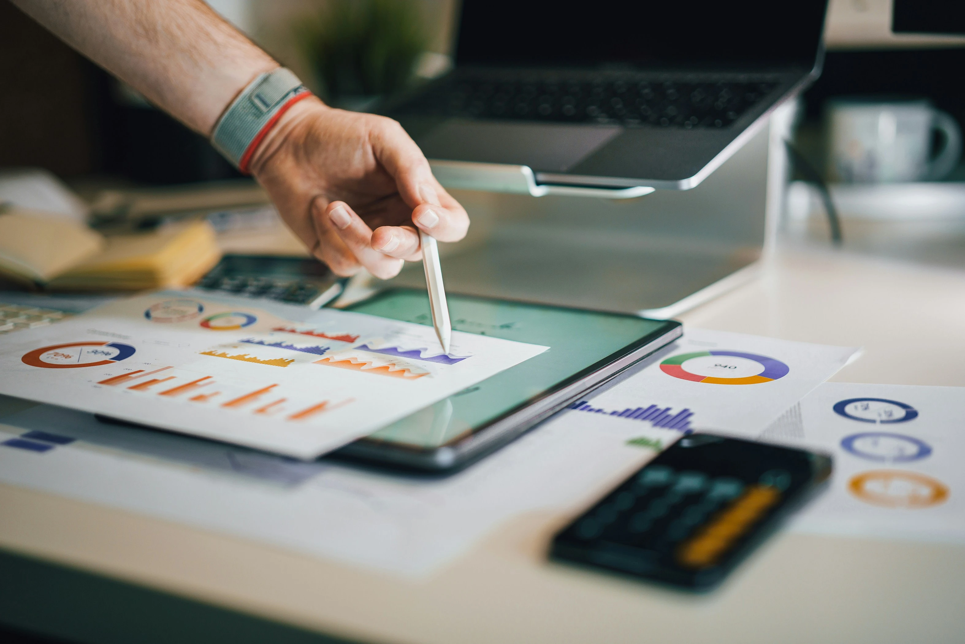 Business analyst reviews colorful charts on tablet with stylus.