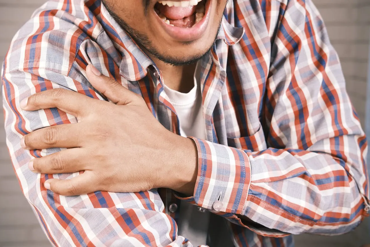Man in red and blue plaid shirt in distress with acute shoulder pain.
