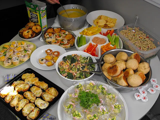 Party buffet food spread with assorted appetizers, dips, vegetables, and rolls.