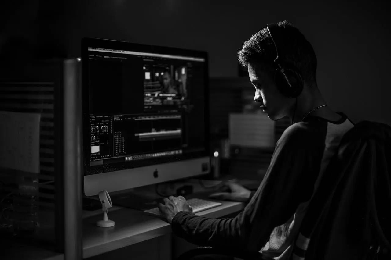 Programmer working intently on an iMac in a moody, high-contrast black and white portrait