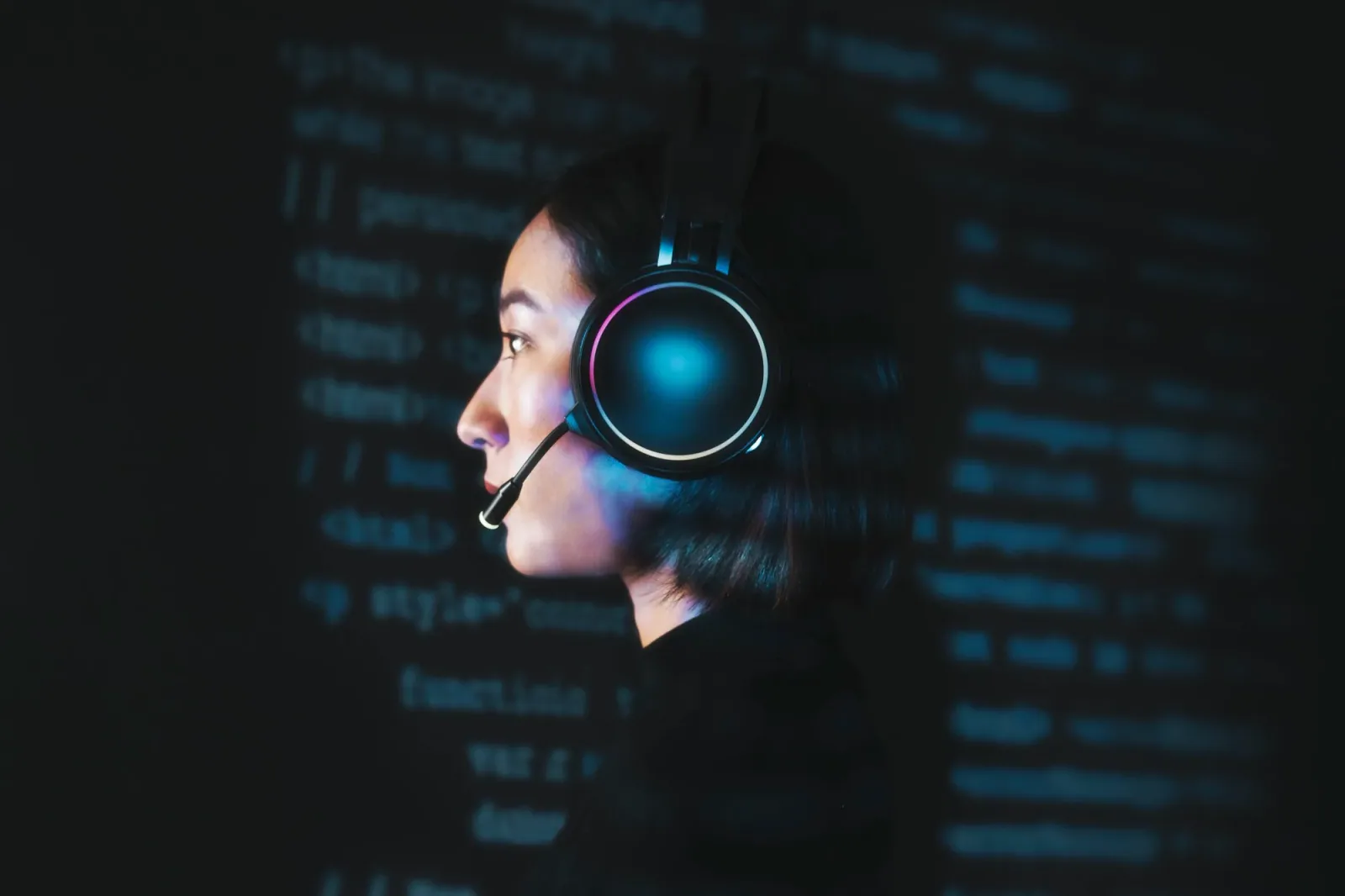Focused female programmer wearing a gaming headset with RGB lights, immersed in technical work.