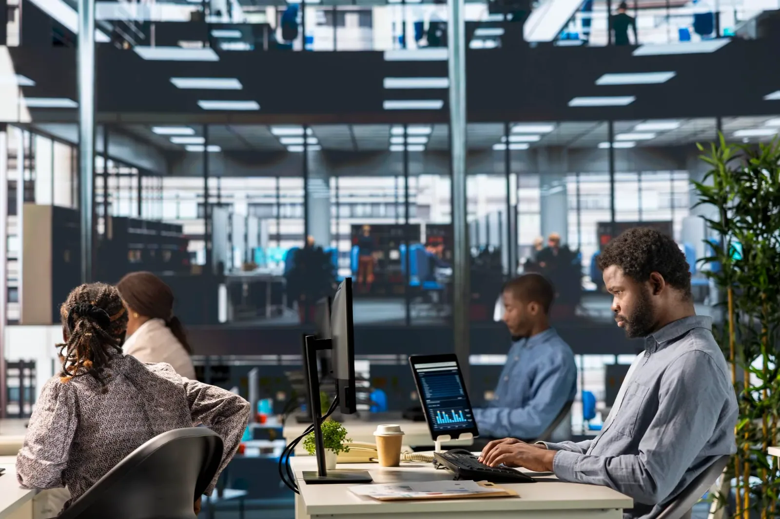 Diverse office team collaborating on laptops, analyzing data in a bright modern workspace.