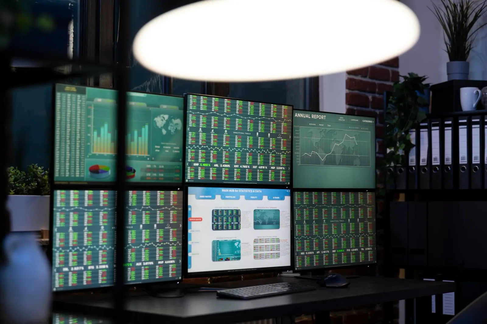 Multi-monitor workstation with charts and data for annual report analysis and market insights.
