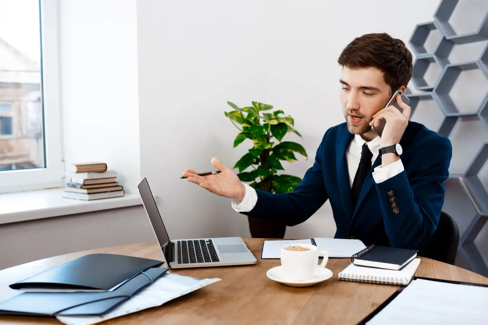 Business professional speaking with a client over the phone during an online consultation with a laptop in the office