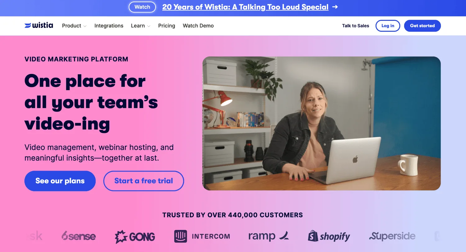 Website landing page shows video platform text, buttons, customer logos, and a woman using a laptop beside a mug.